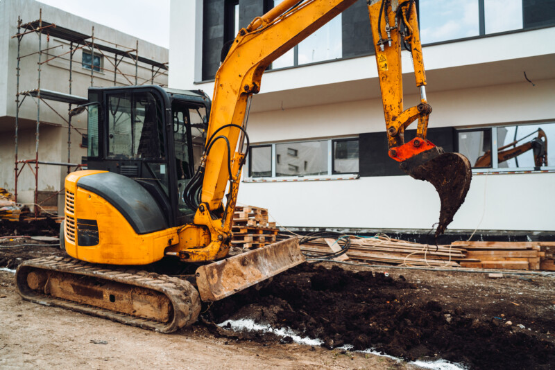 Mini heavy duty excavator moving earth for foundation building. Industrial machinery on construction site,